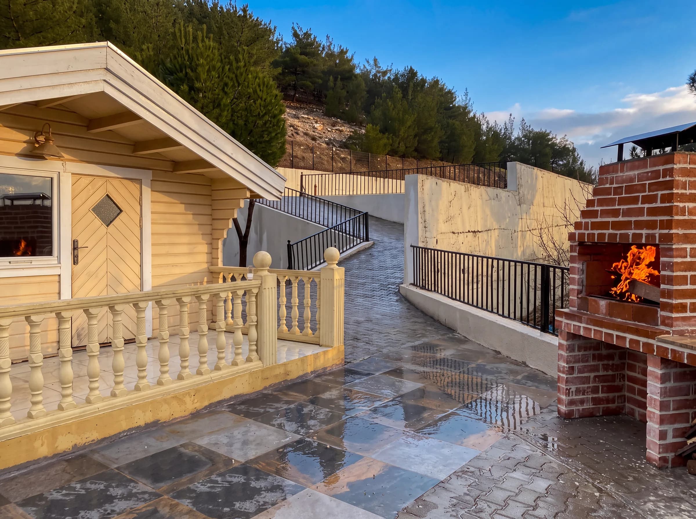 A cabin terrace with a lit brick barbecue grill