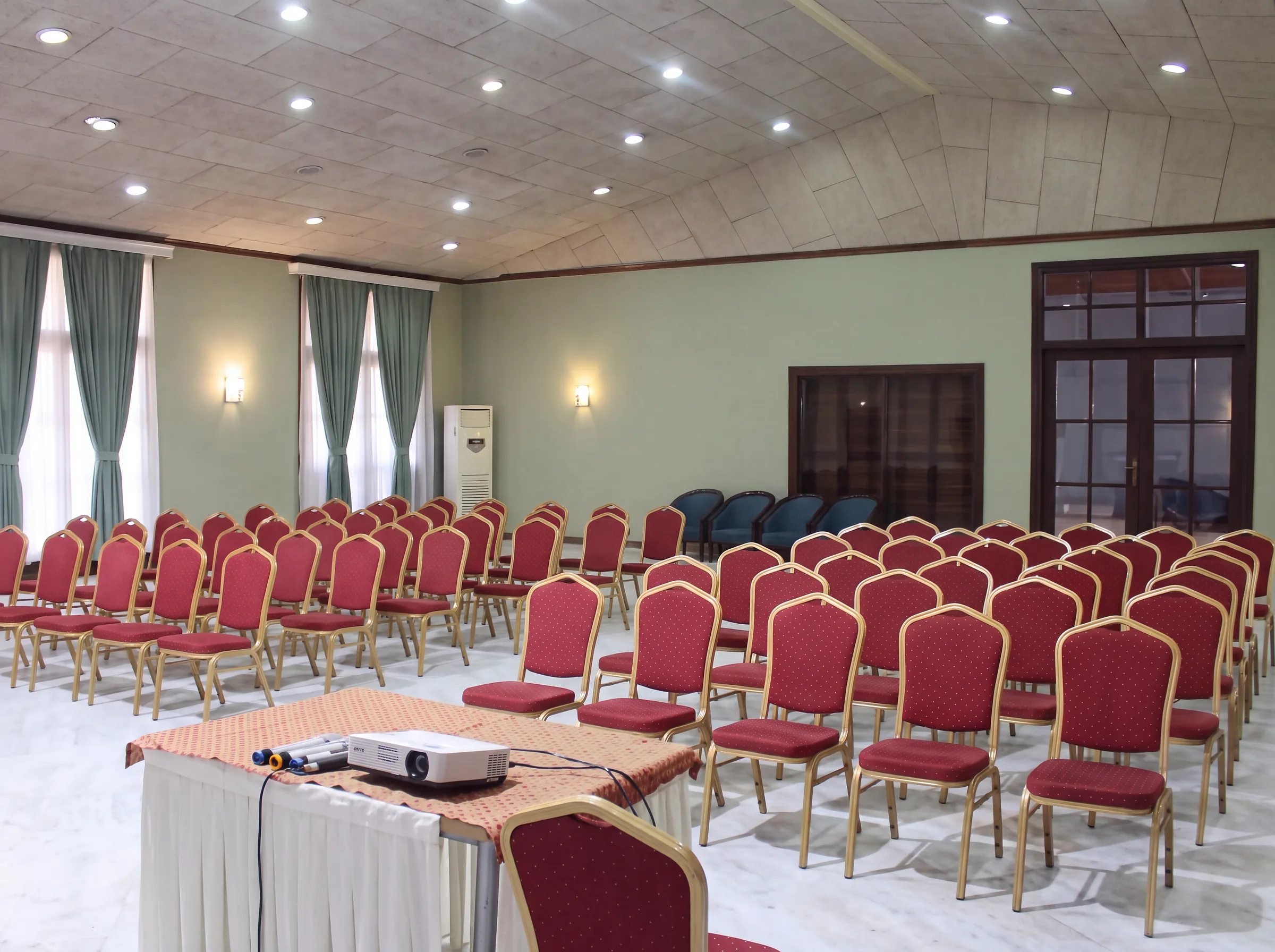 A meeting hall set up with rows of chairs and a projector