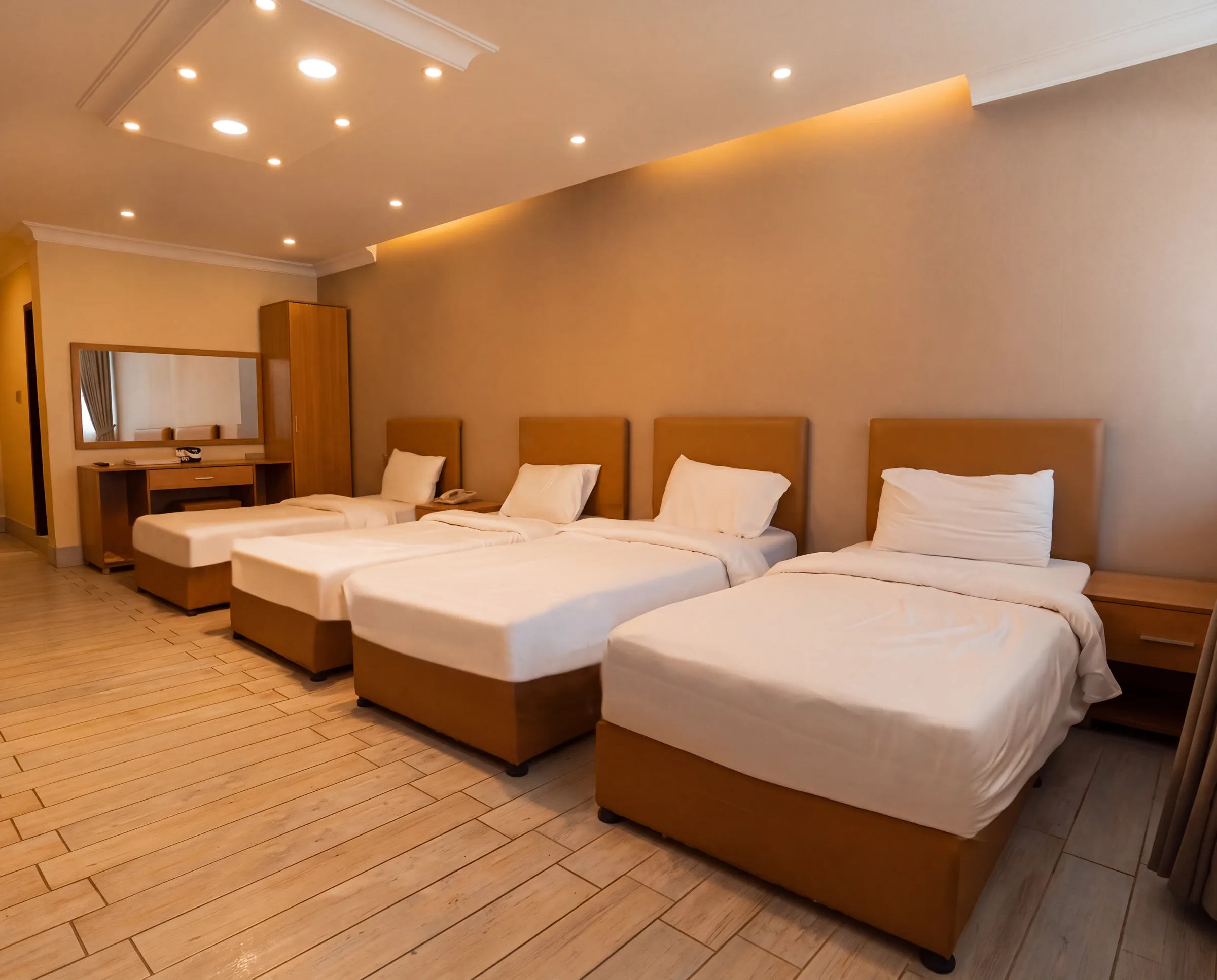 A family room with four single beds side by side, a dressing table with mirror and a wardrobe