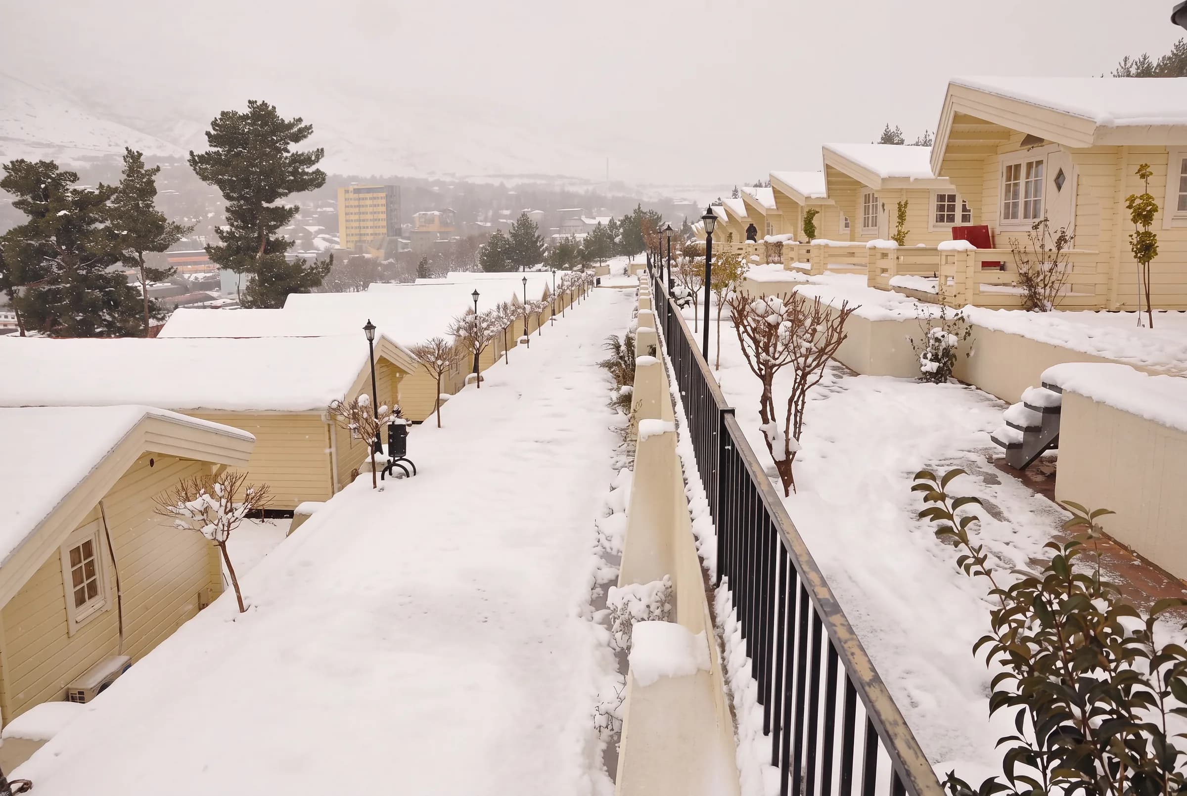 Snow on the cabin roofs and paths, with Shaqlawa beyond.