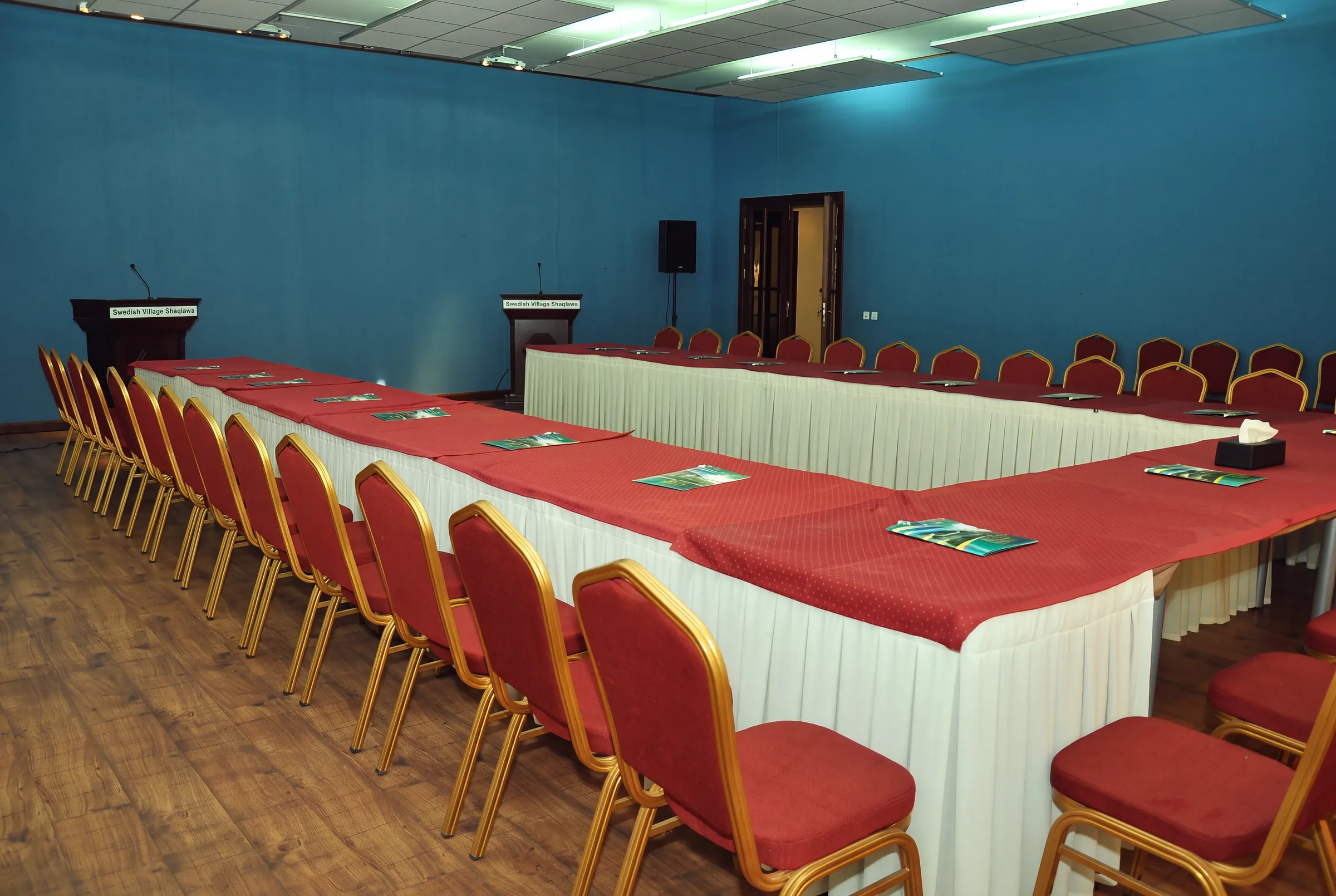 One of our halls, with U-shaped tables, red chairs and two lecterns.