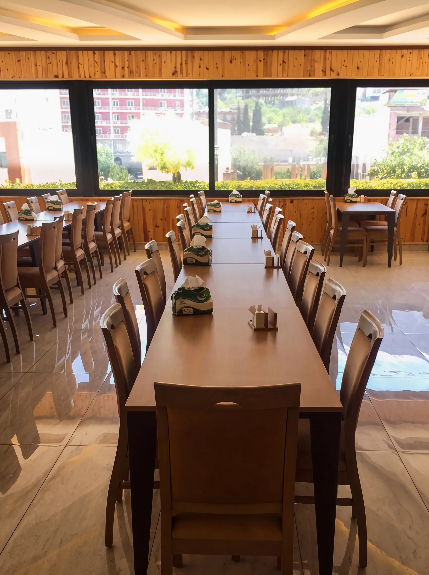 Long dining tables in the restaurant beside large windows